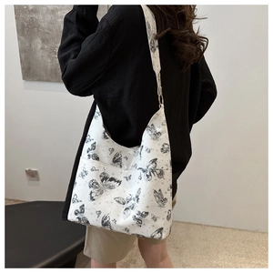 Détail du sac cabas blanc avec imprimés papillons noirs et une large bandoulière