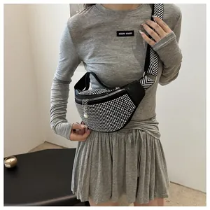 Détail de strass étincelants sur un sac banane noir avec bandoulière à rayures