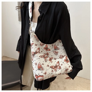Gros plan du motif papillon et de la texture du cuir synthétique du sac cabas
