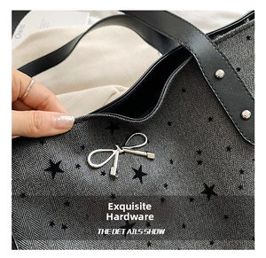 Detail of silver bow pendant and metal hardware on grey herringbone tote bag