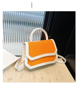 Detail shot of structured orange and white crossbody bag with flap and top handle