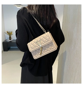 Close-up of beige quilted bag featuring a gold V-logo and decorative chain tassels