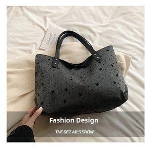 Detail shot of grey tote bag featuring black star print and durable leather handles