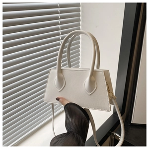 Close-up of white trapezoid handbag showing lychee leather texture and metal hooks