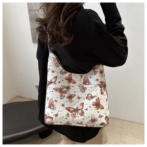 Détail du cabas blanc avec imprimé papillon rouge et anneaux métalliques sur modèle