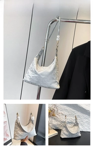 Close-up of grey pleated tote bag with large white bead strap and glossy texture