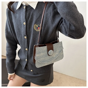 Detail of grey tweed tote bag featuring brown leather trim and silver metal chain strap