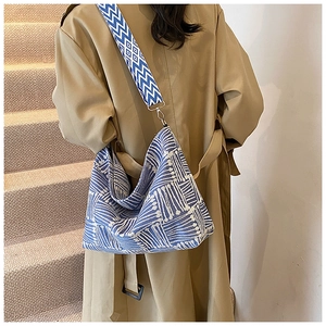 Close-up of blue and white geometric knit texture and wide strap on the canvas hobo bag