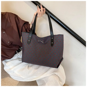 Detail of grey tote bag featuring red heart patterns and a silver metal bow buckle