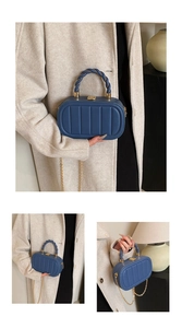 Detail of blue structured handbag with vertical quilting and elegant gold chain strap