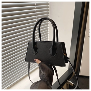 Detail of minimalist black pebbled leather handbag with gold hooks and round handles