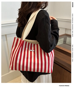 Close-up of red and white striped canvas tote bag with thick woven straps and metal logo