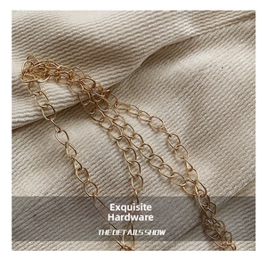 Close-up of elegant gold chain strap on textured beige corduroy fabric detail