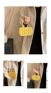 Detailed view of yellow vertical pleated handbag with braided handle and gold chain strap