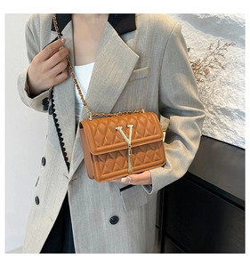 Close-up of brown quilted heart pattern leather bag with gold V logo and tassel detail