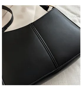 Gros plan sur un sac porté épaule en similicuir noir mat avec coutures verticales