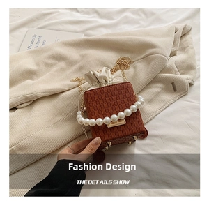 Detail of brown woven mini bucket bag featuring pearl handle and gold chain strap