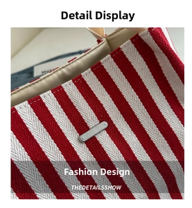 Detail of red and white striped canvas tote with metallic logo plate and fine stitching