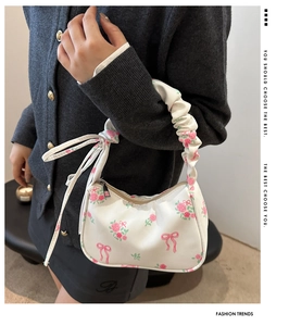 Détail du sac baguette blanc avec motifs de roses roses et poignée à plis doux