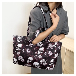 Gros plan d'un grand sac cabas avec motif crâne et fleurs violettes sur la bandoulière