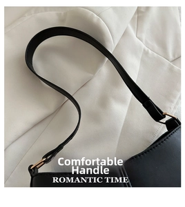 Détail de la bandoulière en cuir noir avec boucle dorée sur un sac sous le bras