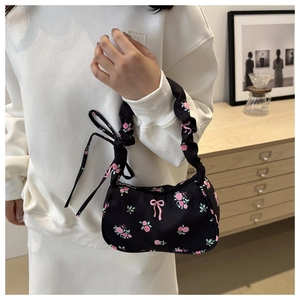 Détail du sac à bandoulière en nylon noir avec motifs floraux roses et poignée froncée