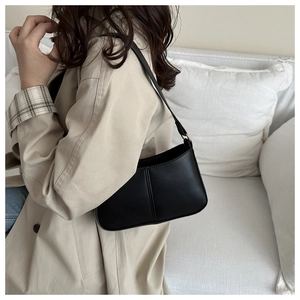 Détail d'un sac hobo noir porté épaule, avec coutures verticales et cuir PU de qualité