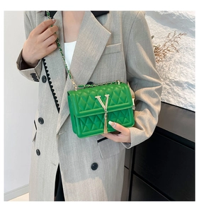 Detailed macro view of green quilted leather bag with V-gold pendant and chain strap