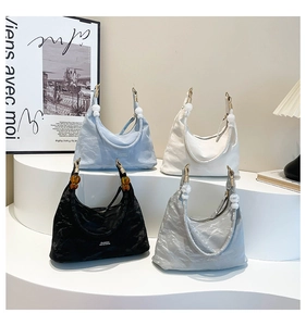 Detail of pleated crescent tote bags with beaded straps in blue, white, black, and silver