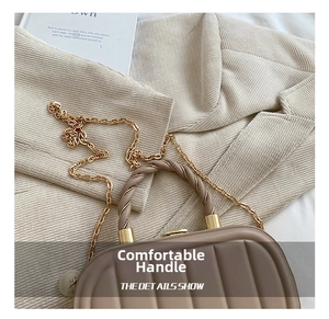 Close-up of vertical textured handbag with twisted handle and gold chain detail