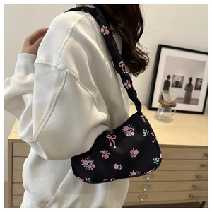 Detailed look at hobo bag with pink floral and bow prints worn on the shoulder