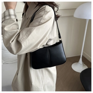 Close-up of minimalist black PU leather underarm bag with sleek gold metal buckle