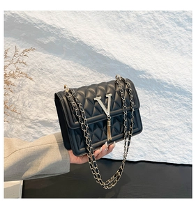 Detail of black quilted chain bag with a metallic V-logo and fringe tassel charm
