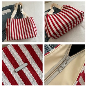 Close-up of red and white striped canvas tote bag with metal zipper and logo plaque