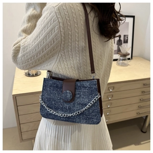 Detail view of navy polka dot tweed crossbody bag with brown leather strap and chain