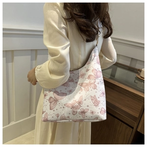 Gros plan d'un sac cabas en toile crème avec motifs de papillons mauves et constellations
