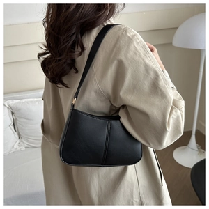 Détail d'un sac sous les bras noir minimaliste avec coutures verticales sur manteau beige