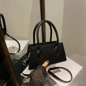 Minimalist black faux leather handbag with golden hardware and adjustable strap
