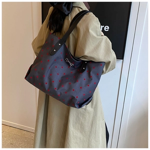 Detailed view of grey tote bag with red polka dots featuring a silver bow and leather straps