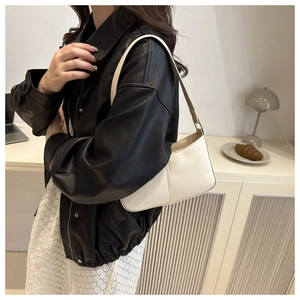 Gros plan d'un sac hobo crème minimaliste porté avec une veste en cuir et jupe dentelle
