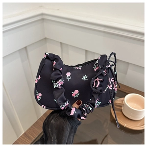 Détail d'un sac à fleurs noir avec rubans roses et une poignée froncée style chouchou