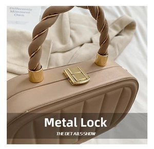 Close-up of golden hardware lock and twisted chain handle on quilted beige handbag