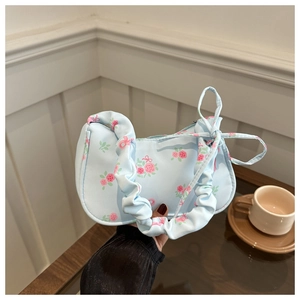 Détail du sac en toile bleu clair à motif floral avec bandoulière froncée et nœud rose
