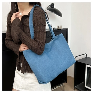Blue canvas tote bag shown as a side view on model for daily shoulder carry use