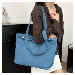 Detailed view of durable blue denim tote bag featuring sturdy handles and secure zipper top