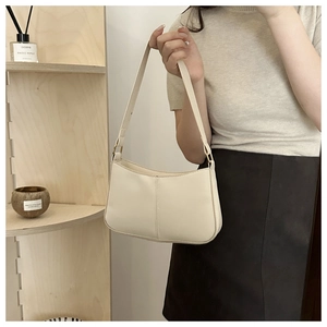 Détail du sac baguette beige en similicuir montrant les coutures et la bandoulière