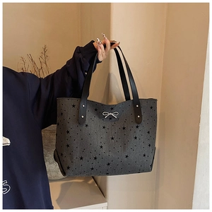 Close-up of star pattern tote bag with silver bow detail and leather handle