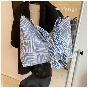 Detail view of woven hobo bag with geometric textures and a wide patterned shoulder strap