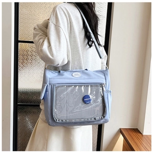 Close-up of light blue tote bag with transparent PVC window and fashion badge detail