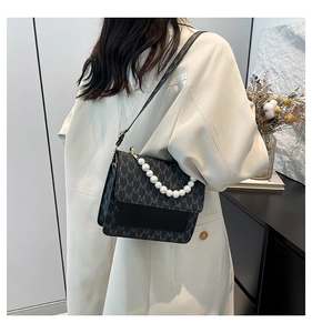Detail of crossbody bag with M-letter print and elegant white pearl handle chain